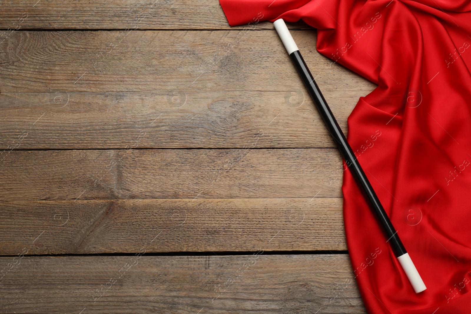 Photo of Beautiful black magic wand and red fabric on wooden table, top view. Space for text