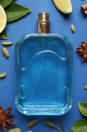 Flat lay composition with bottle of perfume and fresh citrus fruit on blue background