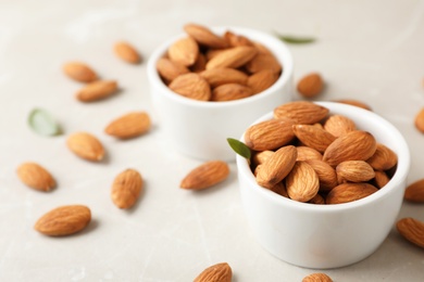 Photo of Tasty organic almond nuts in bowls on table. Space for text
