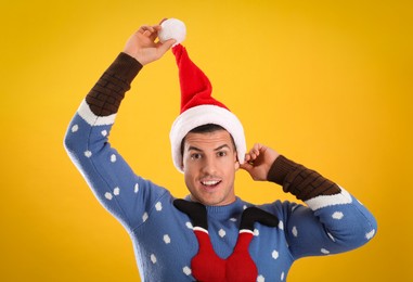 Photo of Surprised man wearing Santa hat on yellow background