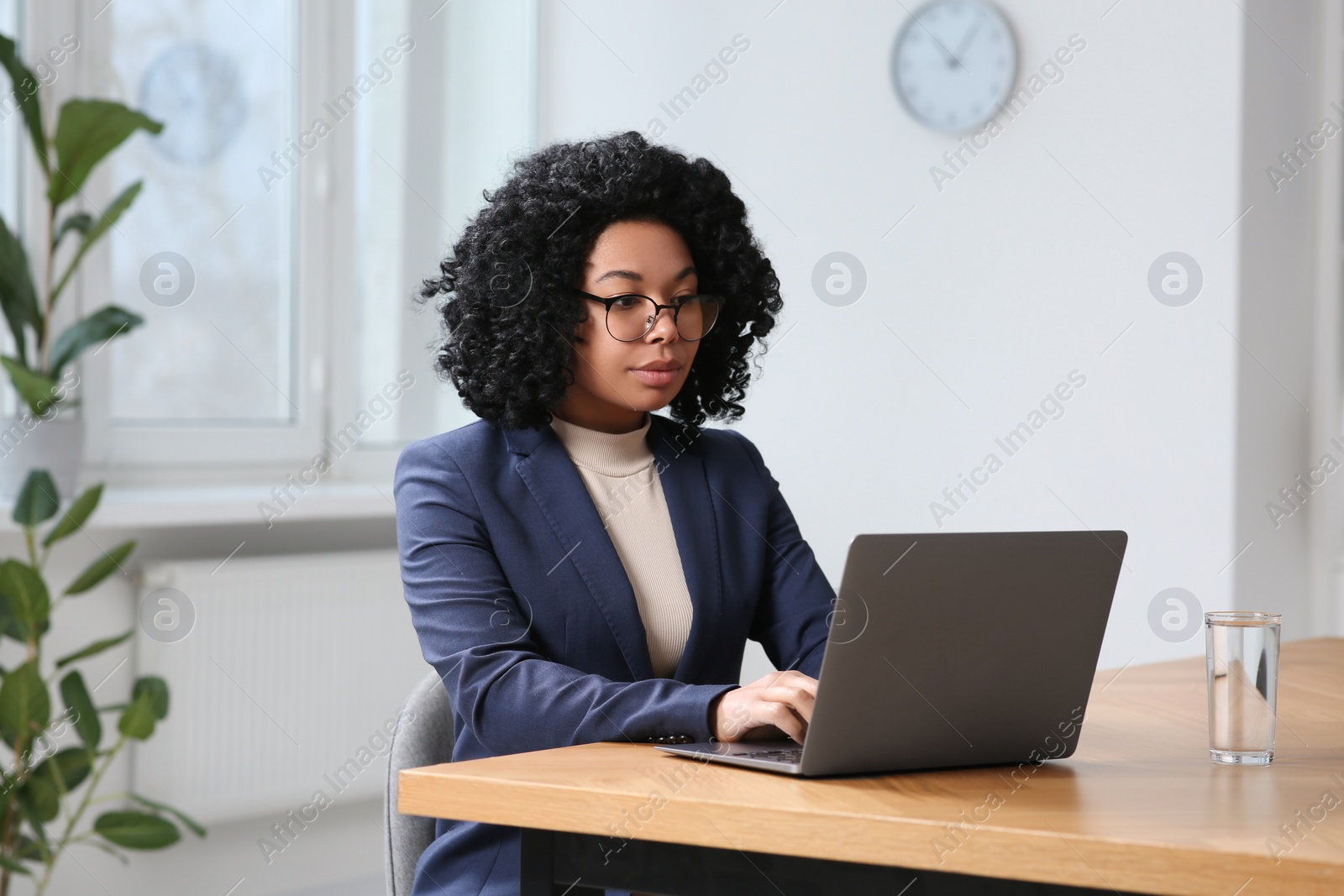 Photo of Young woman working on laptop at table in office