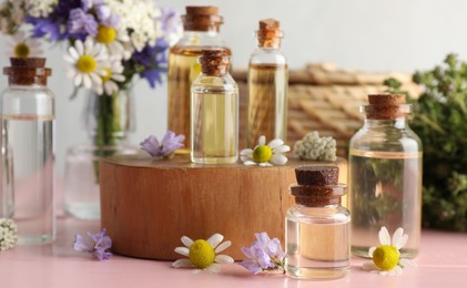 Photo of Aromatherapy. Different essential oils and flowers on pink wooden table