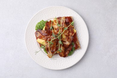 Photo of Tasty sandwich with bacon and microgreens on light grey table, top view