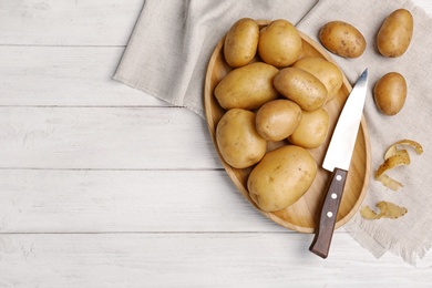 Flat lay composition with fresh organic potatoes and space for text on wooden background