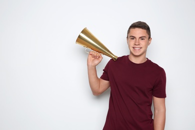 Photo of Teenage boy with megaphone on white background. Space for text