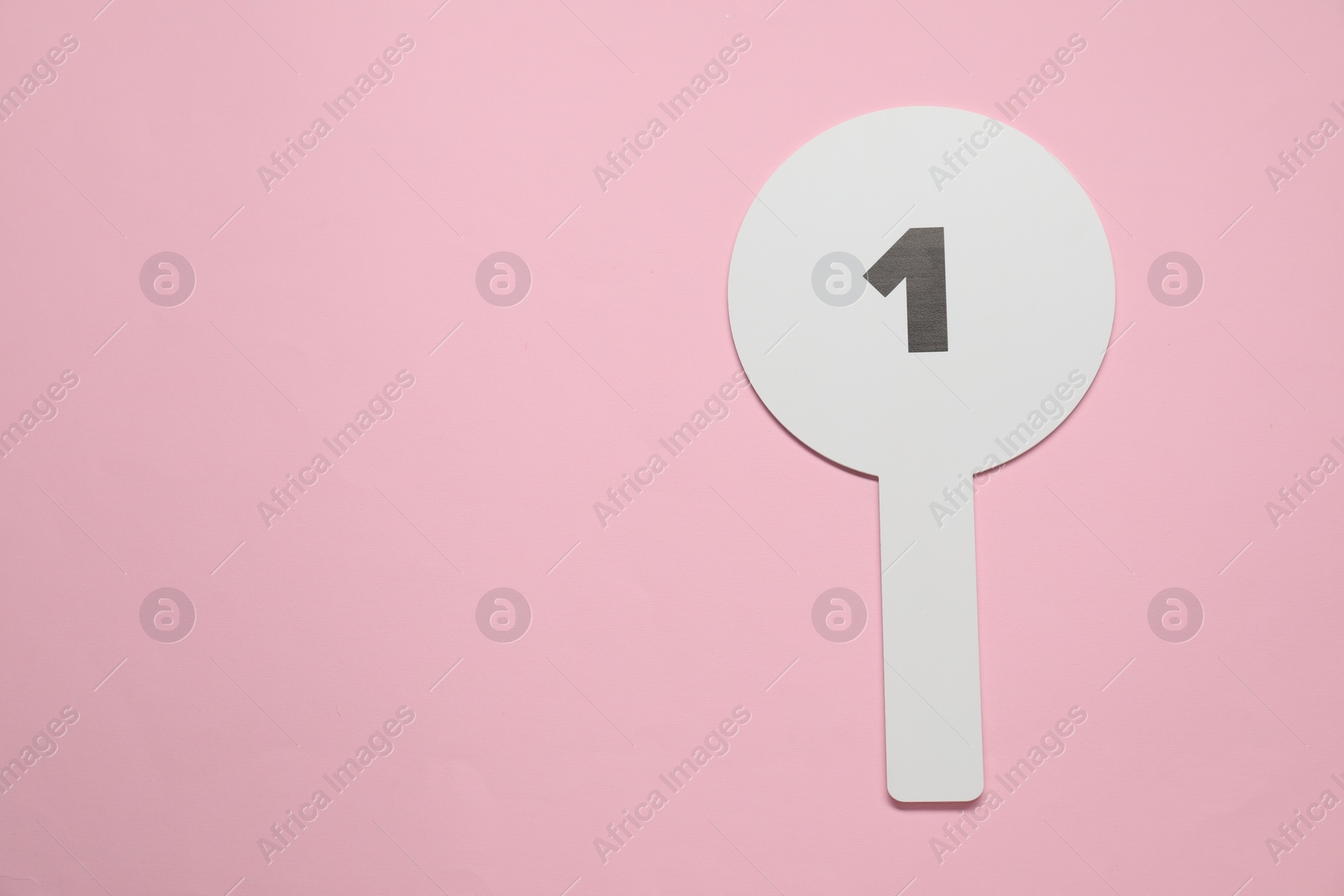 Photo of Auction paddle with number 1 on pink background, top view. Space for text