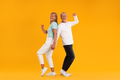 Photo of Senior couple dancing together on orange background