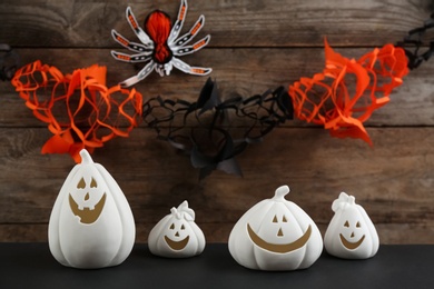 Photo of Jack-o-Lantern holders on black table against decorated wooden background. Halloween decor