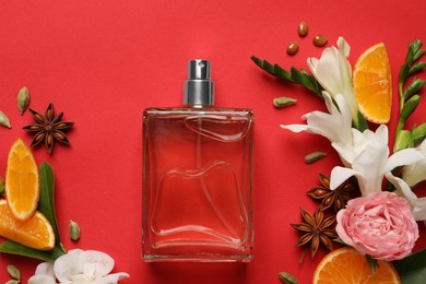 Photo of Flat lay composition with bottle of perfume and fresh citrus fruits on red background