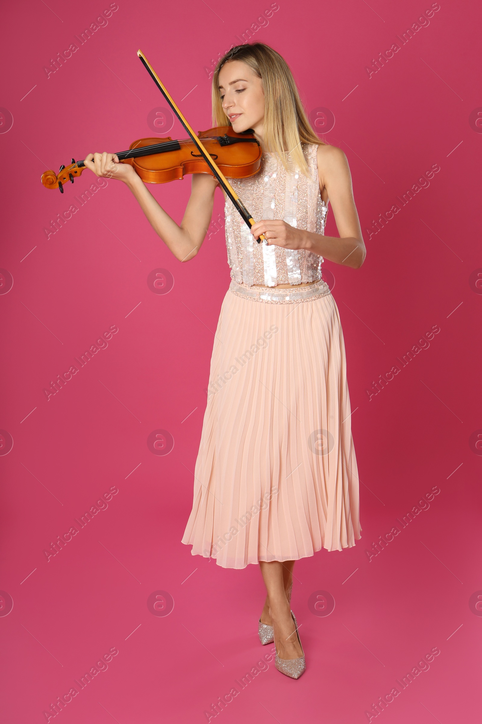 Photo of Beautiful woman playing violin on pink background