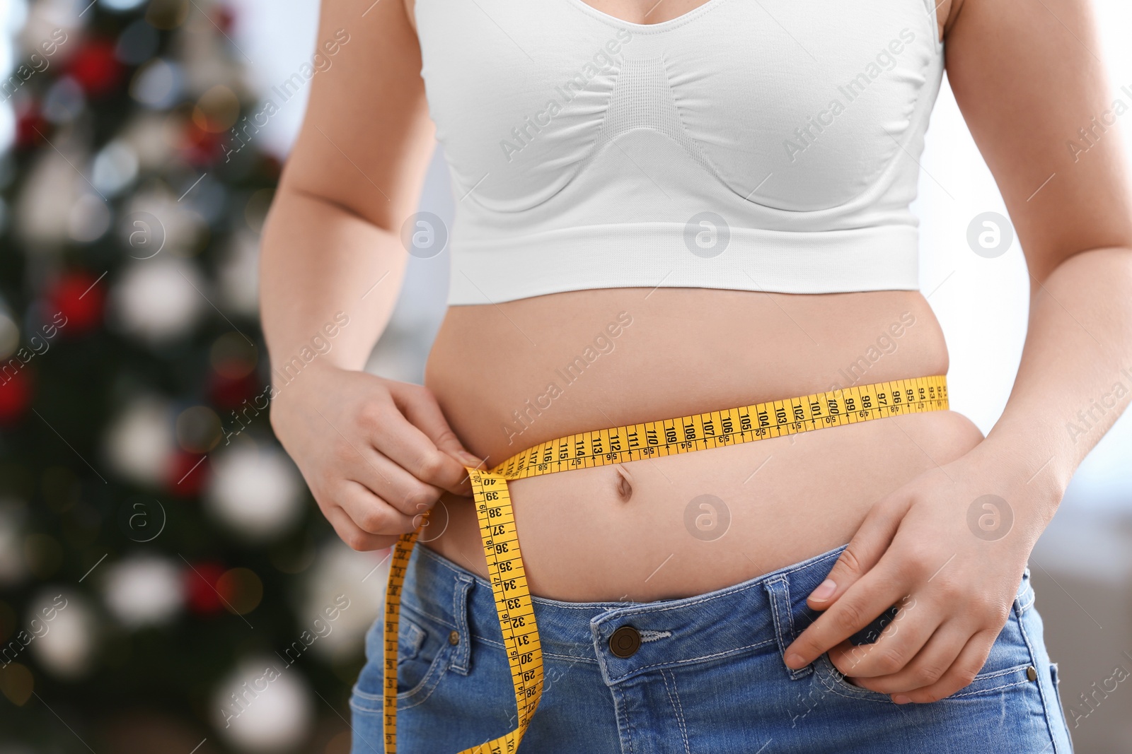 Photo of Woman with measuring tape indoors, closeup. Overweight problem after New Year party