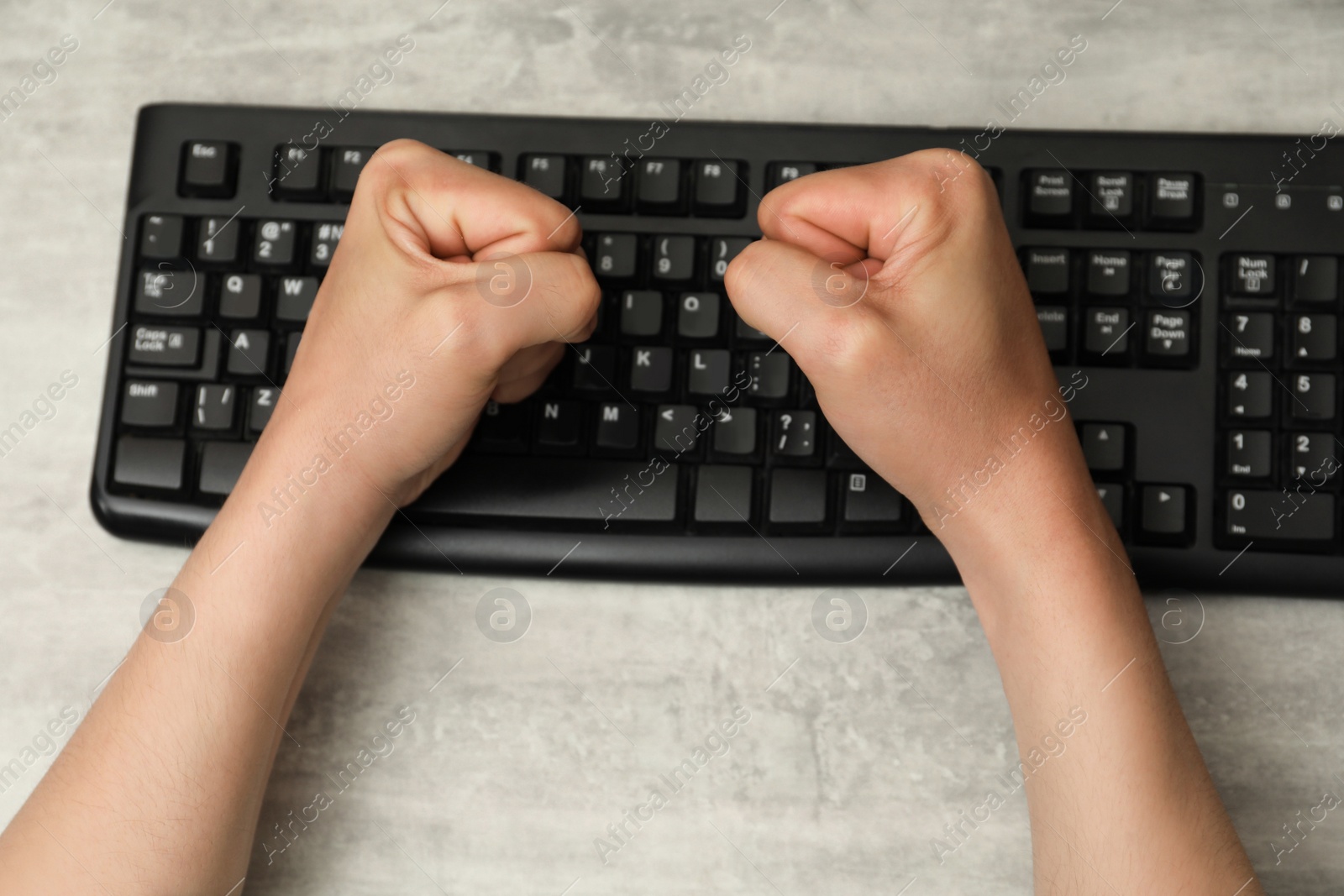 Photo of Angry man with clenched fists at table during work, top view