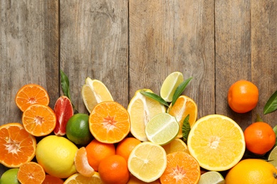 Photo of Different citrus fruits on wooden background, top view. Space for text