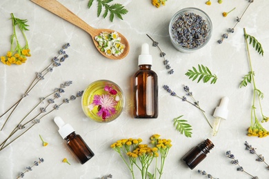 Flat lay composition with essential oils and flowers on light background