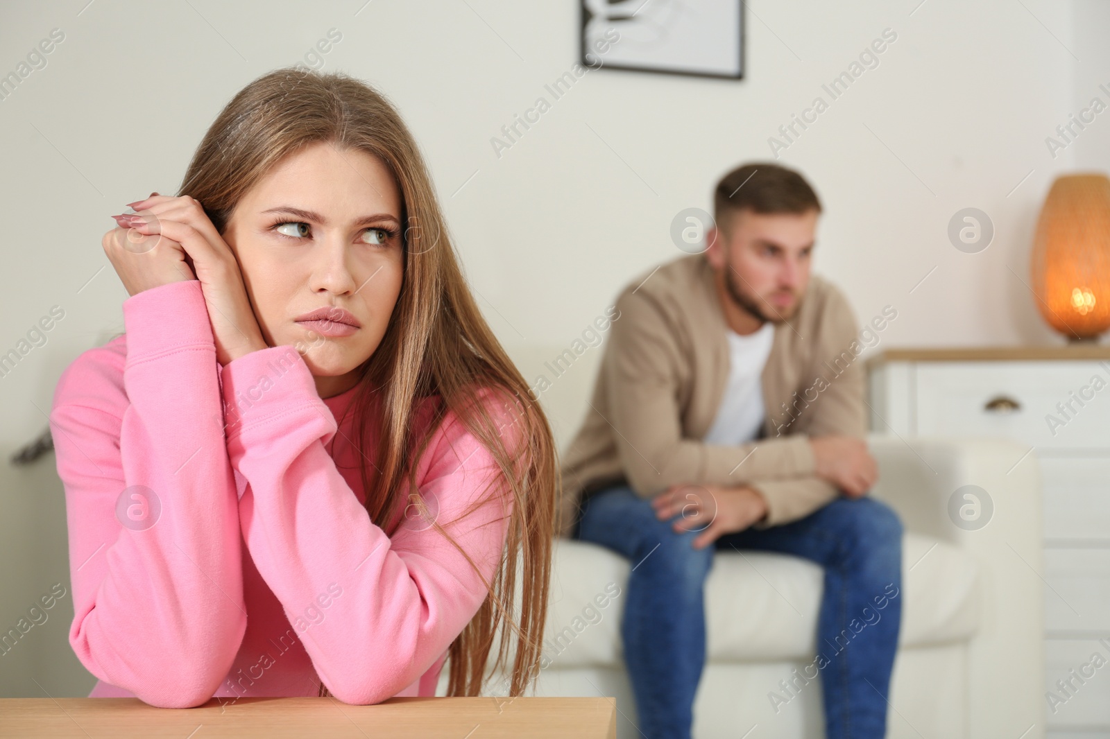 Photo of Young couple ignoring each other after argument in living room. Relationship problems