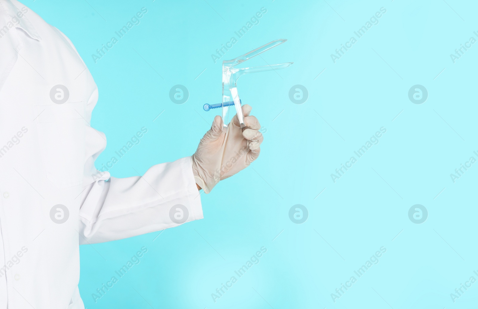 Photo of Male doctor holding disposable speculum on color background, closeup with space for text. Medical object