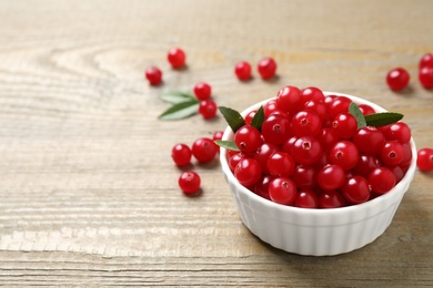 Photo of Tasty ripe cranberries on wooden table, closeup. Space for text