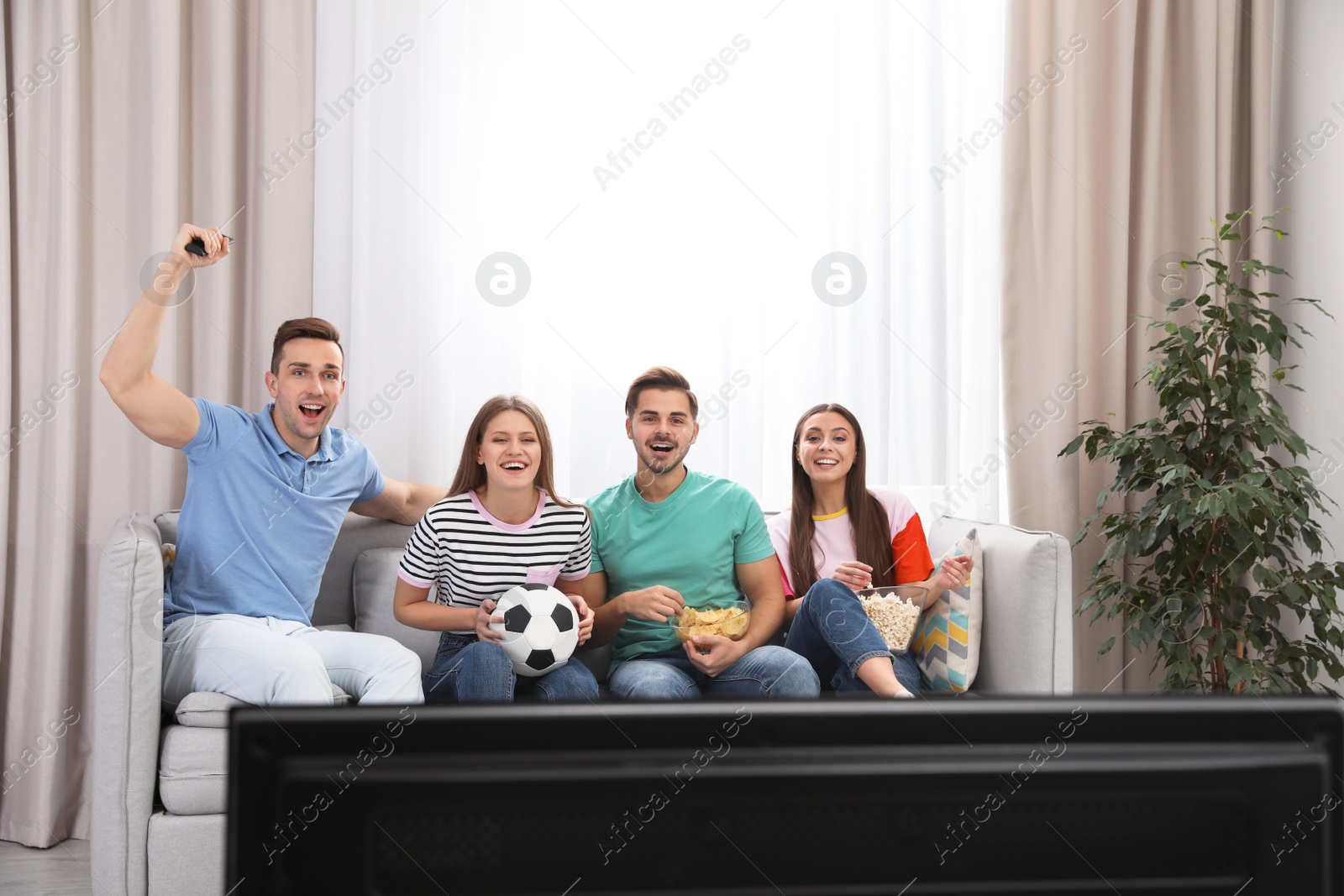 Photo of Group of people watching soccer match on TV at home