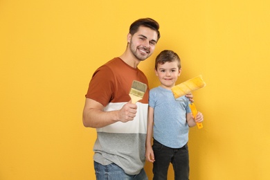 Dad and his son with painting tools on color background