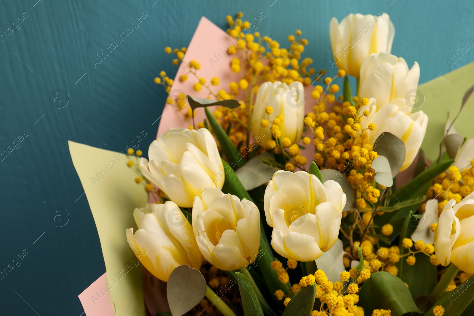 Photo of Bouquet of beautiful spring flowers near turquoise wooden wall, closeup