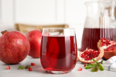 Photo of Glass of pomegranate juice and fresh fruits on light table