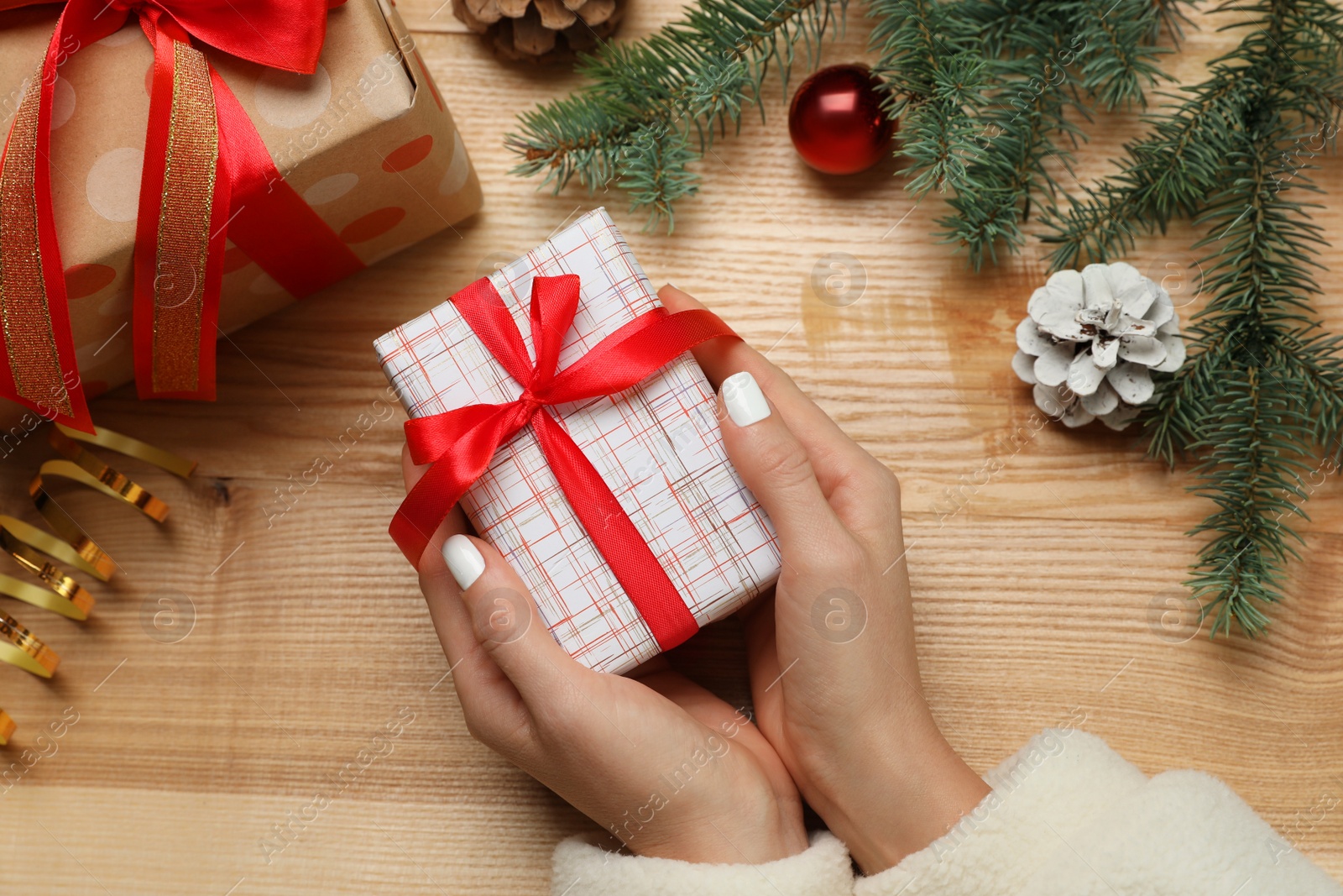 Photo of Woman with Christmas gift at wooden table, top view