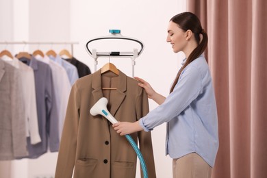 Photo of Woman steaming jacket on hanger in room