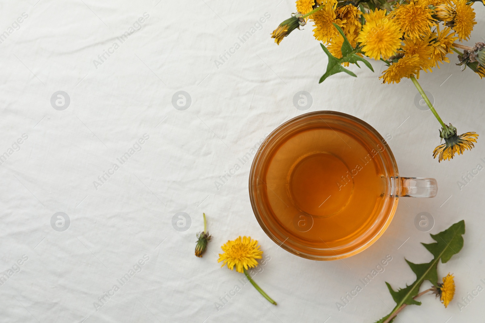 Photo of Delicious fresh tea and dandelion flowers on white table, flat lay. Space for text