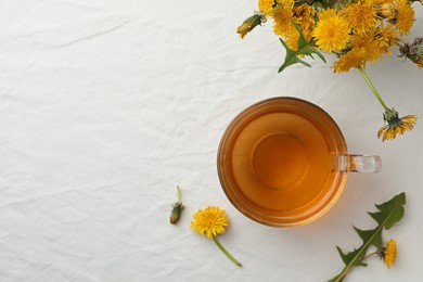 Photo of Delicious fresh tea and dandelion flowers on white table, flat lay. Space for text