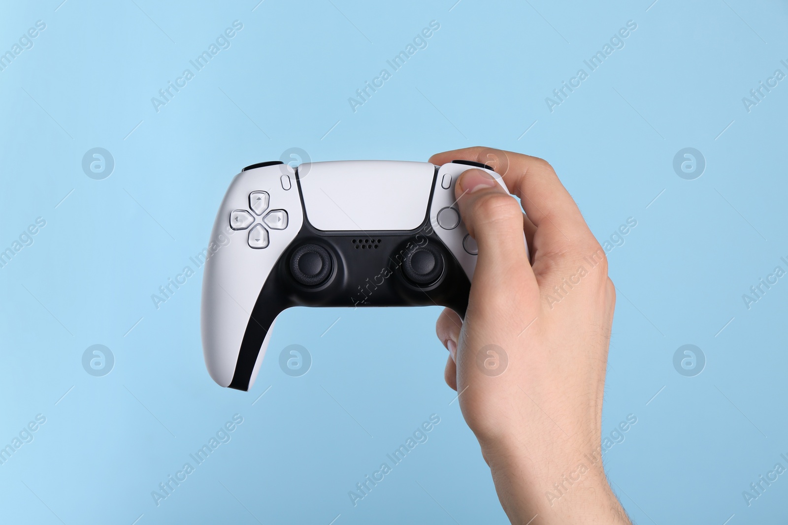 Photo of Man using wireless game controller on light blue background, closeup