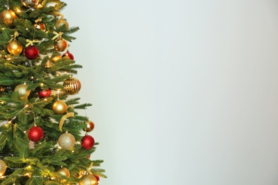 Beautiful Christmas tree with fairy lights and festive decor on white background