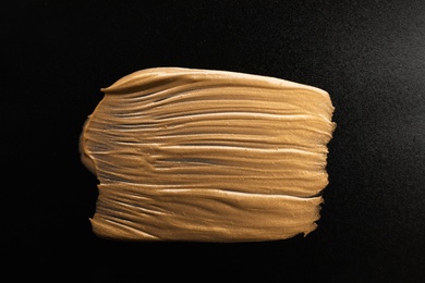 Photo of Golden paint brush stroke on black background