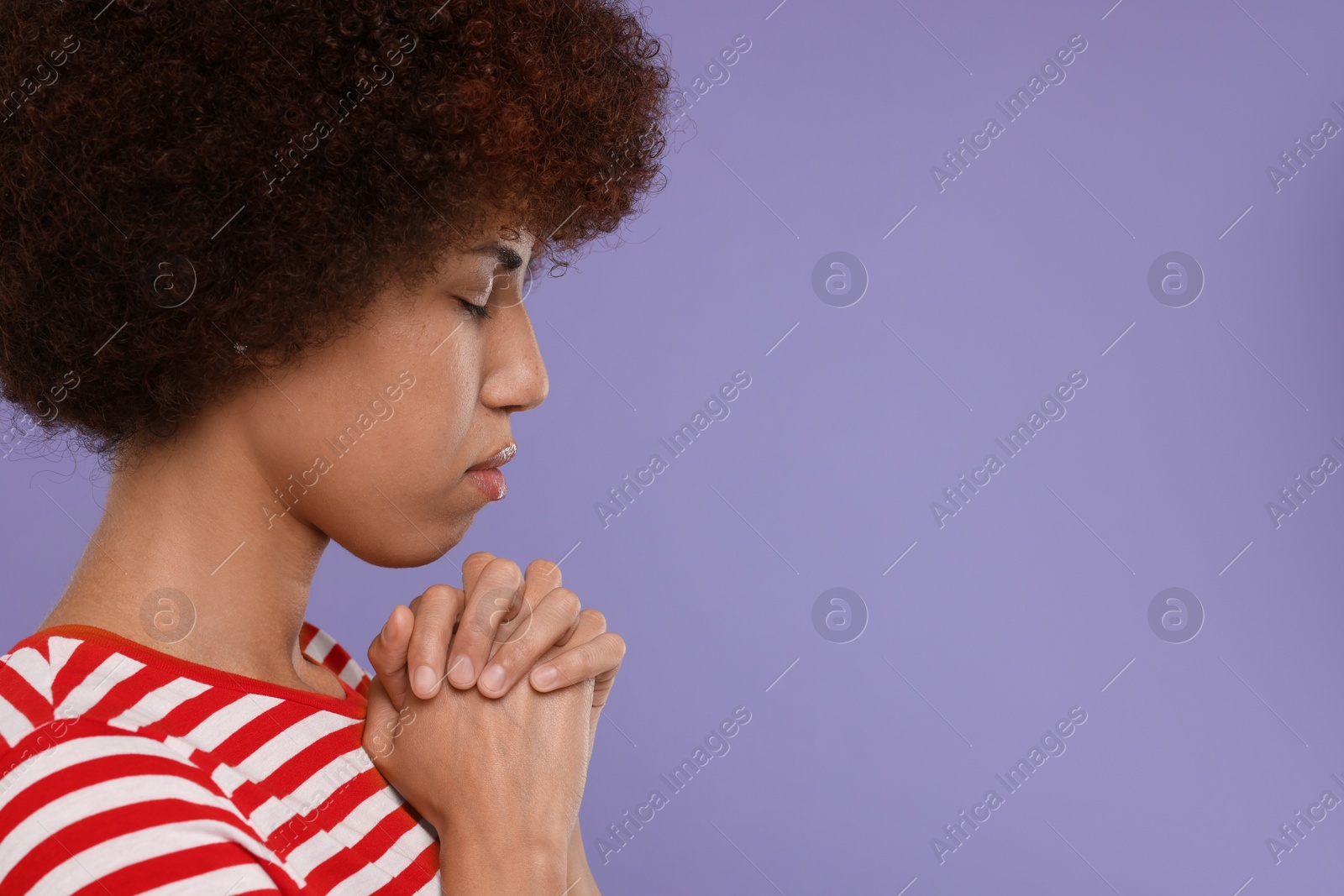 Photo of Woman with clasped hands praying to God on purple background. Space for text
