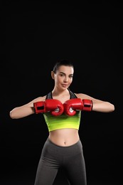Portrait of beautiful woman in boxing gloves on black background