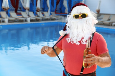 Authentic Santa Claus with bottle of beer near pool at resort