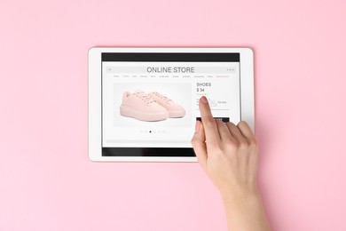 Photo of Woman with tablet shopping online on pink background, top view