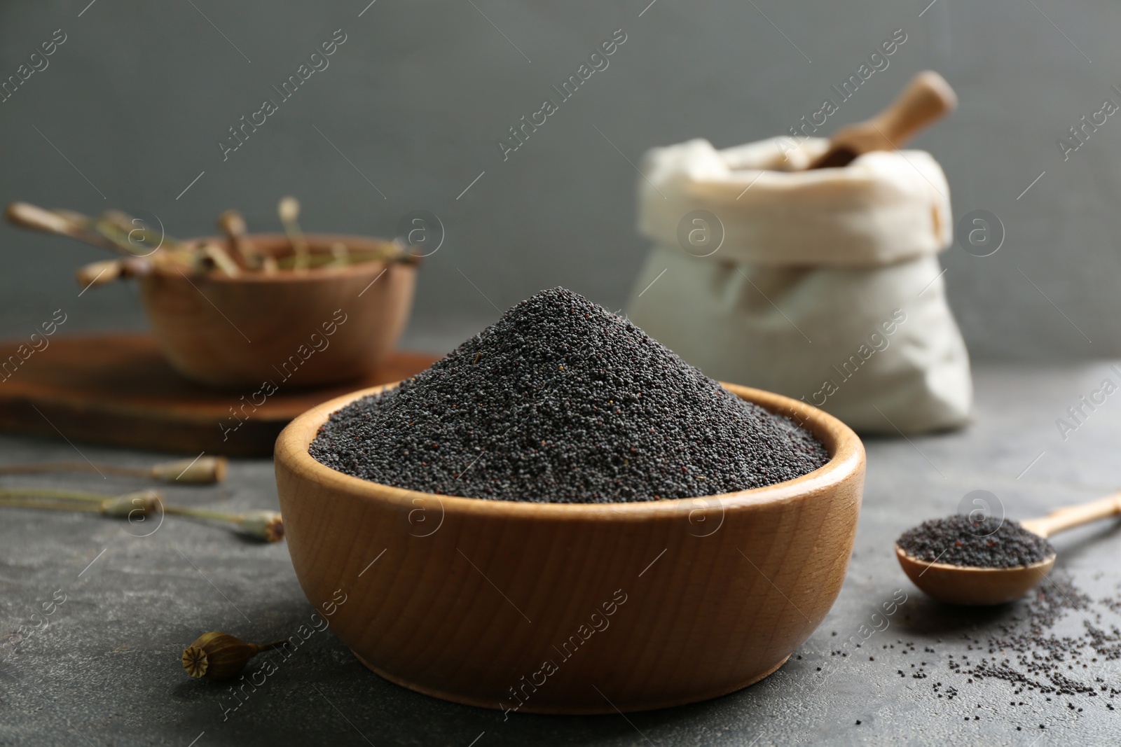 Photo of Poppy seeds in bowl on grey table