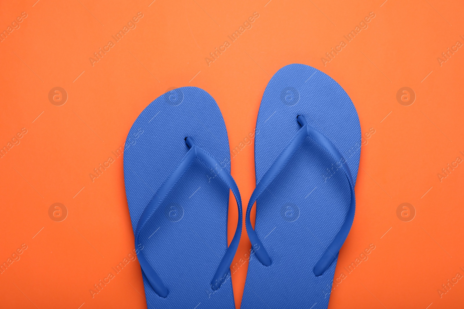 Photo of Stylish blue flip flops on orange background, top view