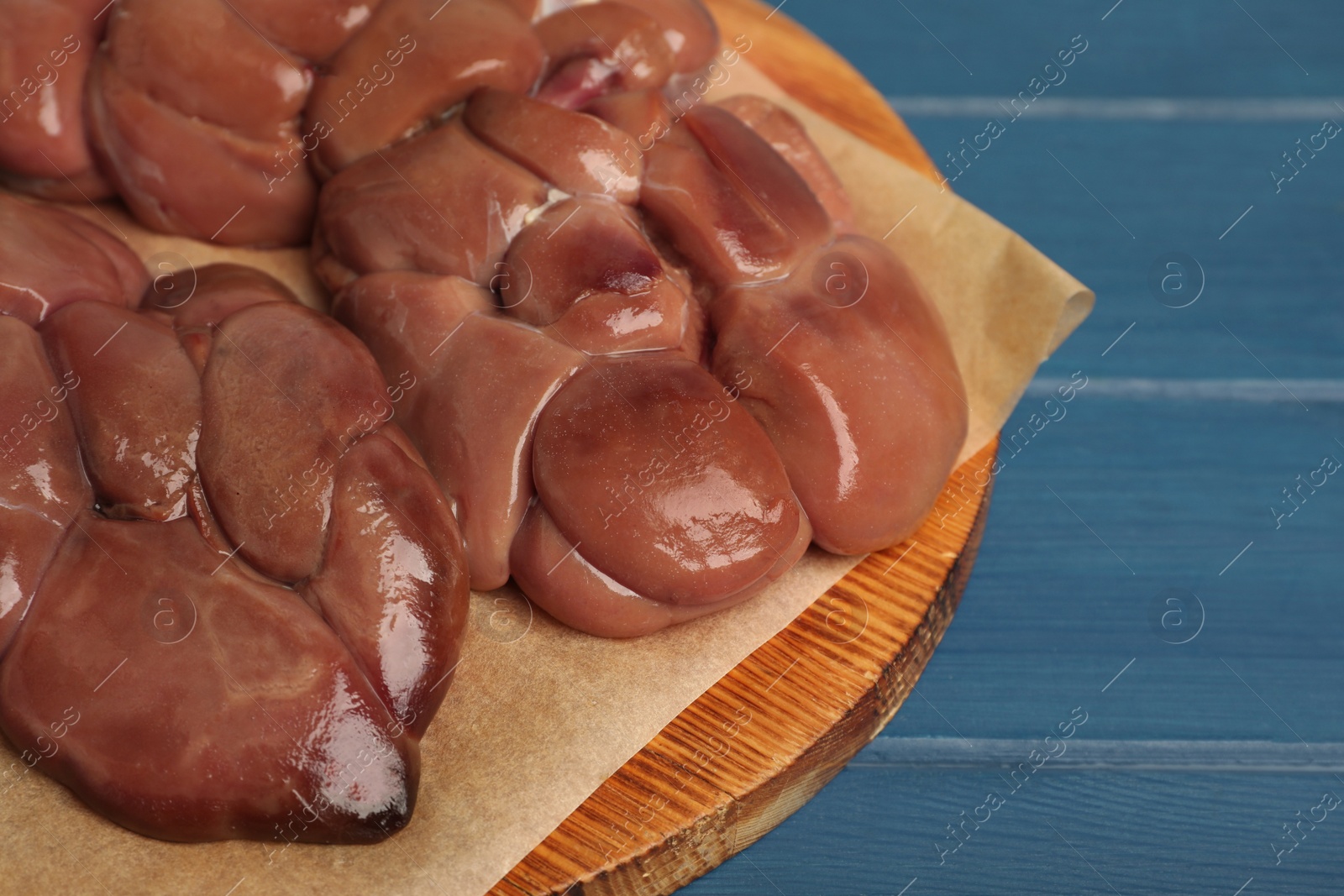Photo of Fresh raw kidney meat on blue wooden table, closeup