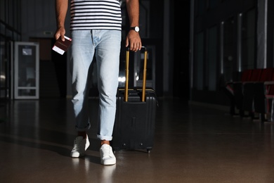 Man with black travel suitcase in airport. Space for text