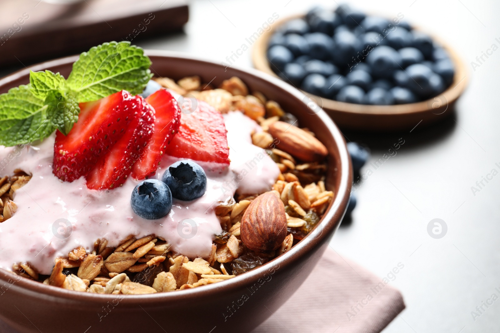 Photo of Delicious yogurt with granola and berries served on grey table, closeup