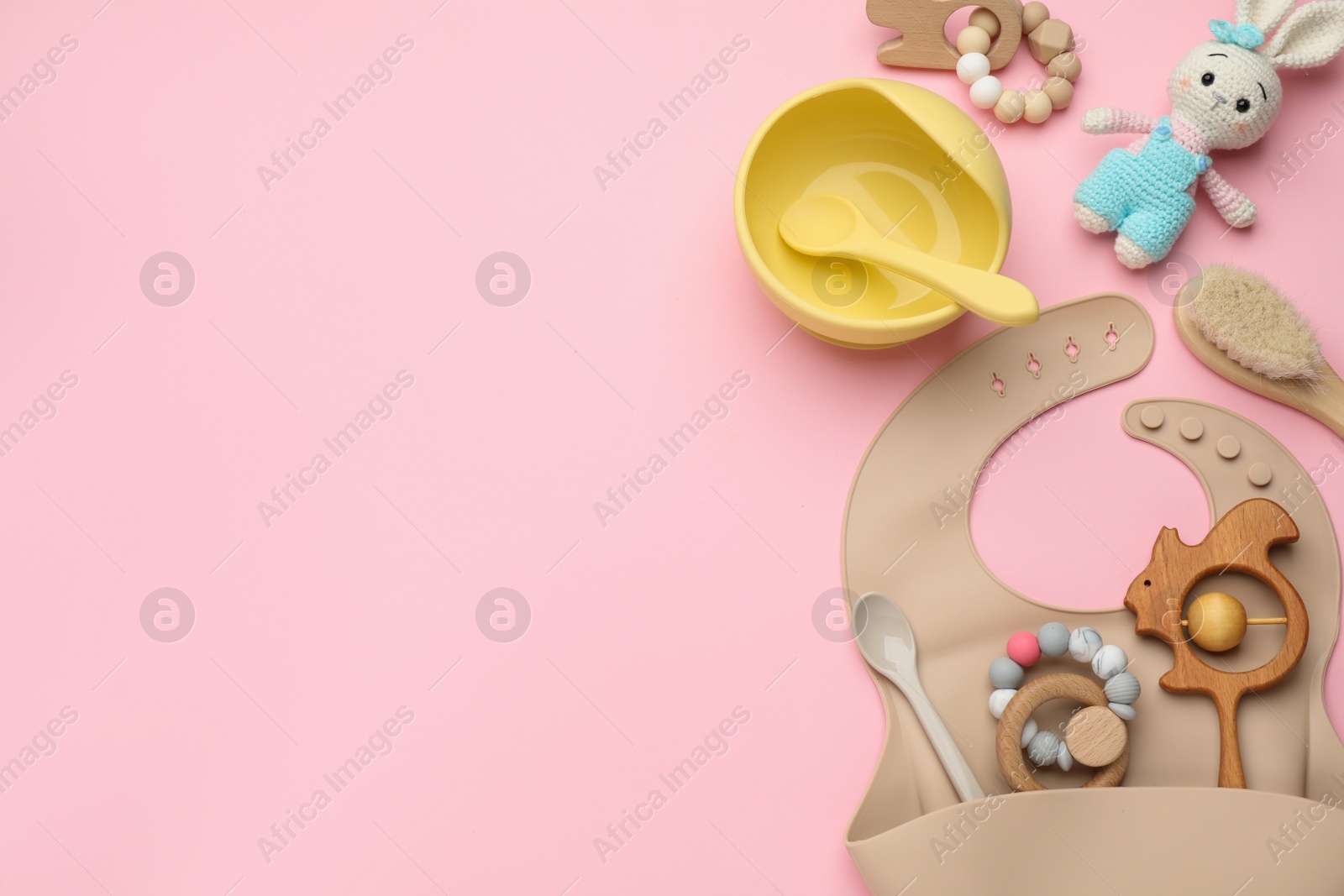 Photo of Flat lay composition with baby accessories and bib on pink background, space for text