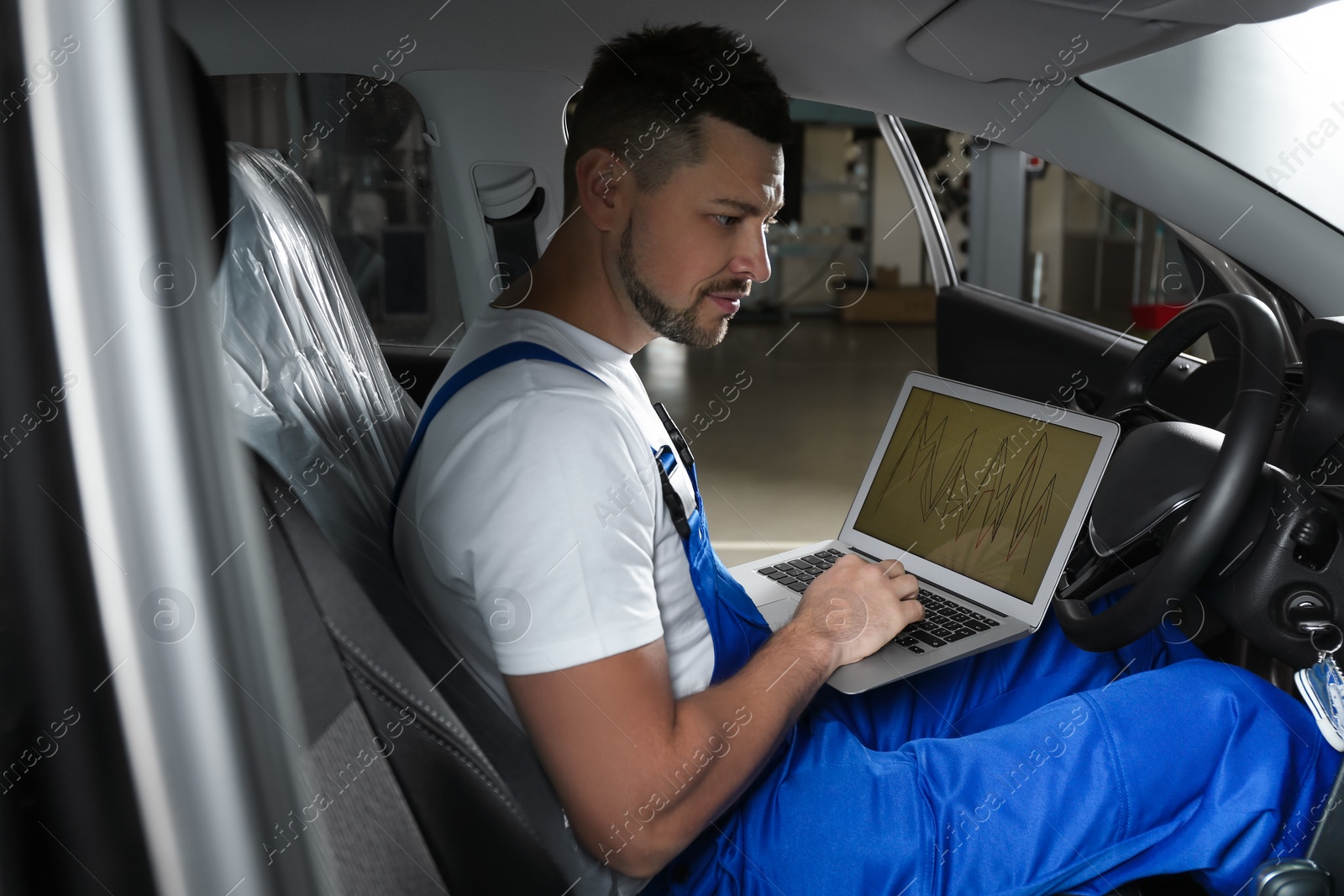 Photo of Mechanic with laptop doing car diagnostic at automobile repair shop