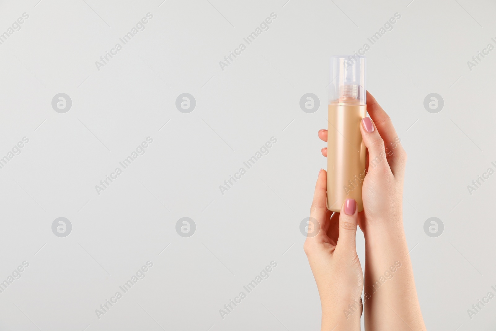 Photo of Woman holding spray bottle with hair thermal protection on white background, closeup. Space for text