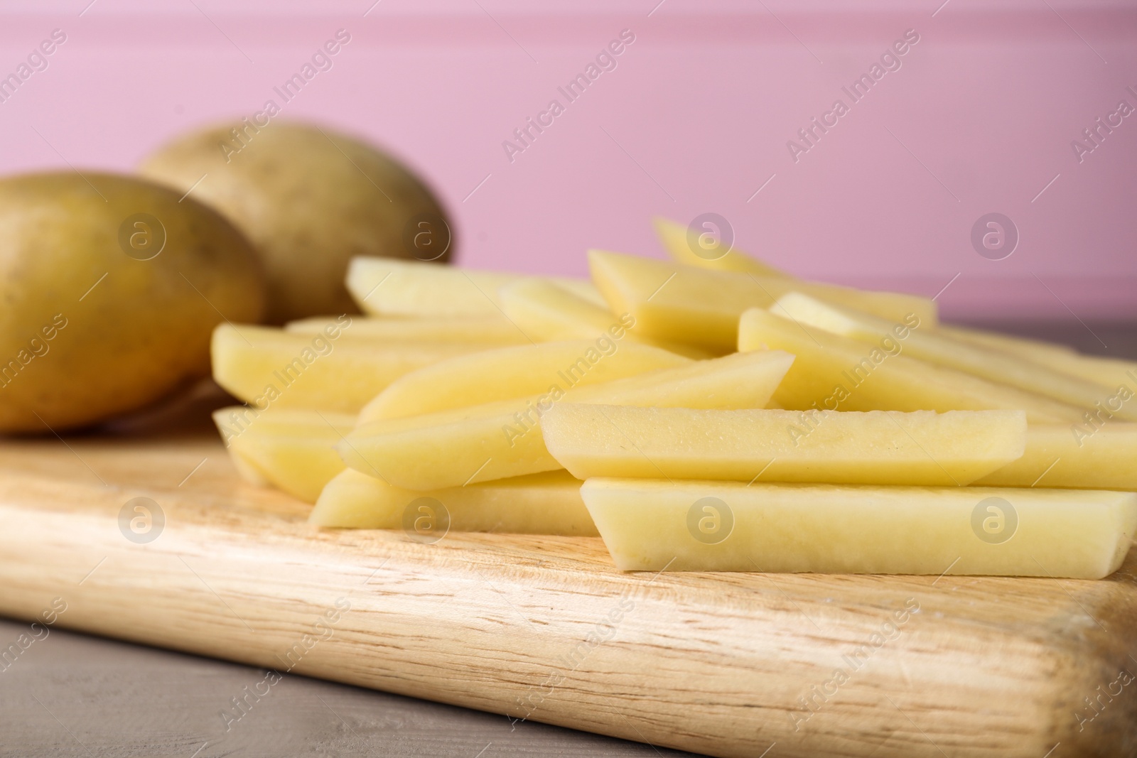 Photo of Whole and cut raw potatoes on wooden board, closeup