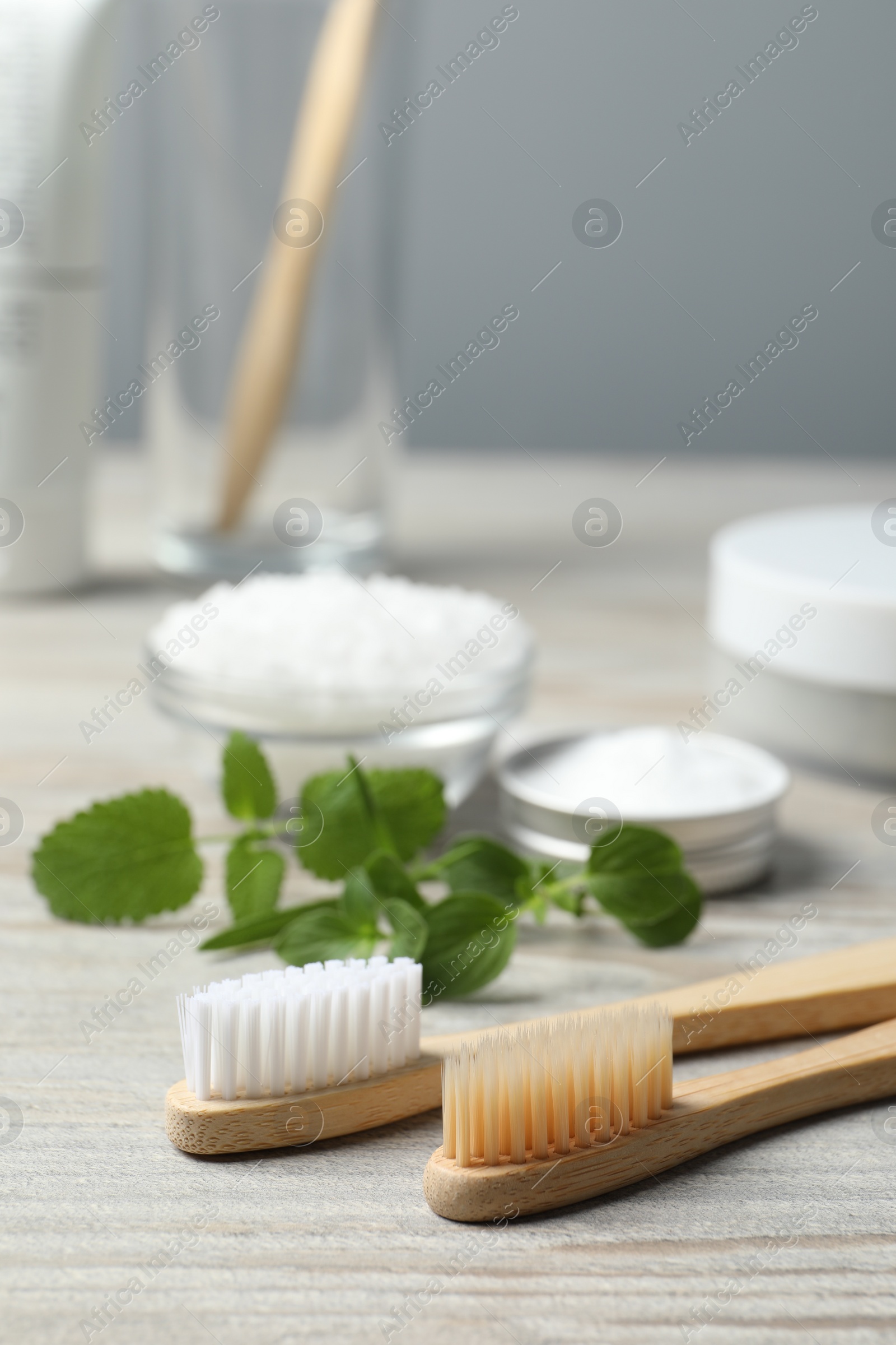 Photo of Toothbrushes and green herbs on wooden table, closeup