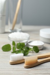 Toothbrushes and green herbs on wooden table, closeup