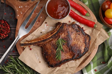 Photo of Tasty grilled meat, rosemary and marinade served on wooden table, flat lay