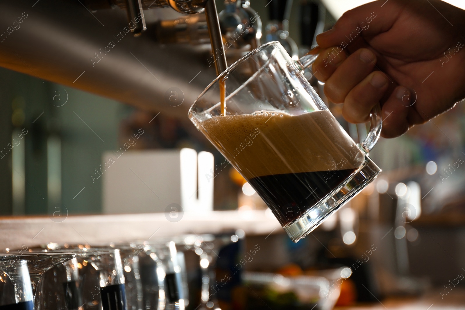 Photo of Bartender pouring beer into glass in pub, closeup