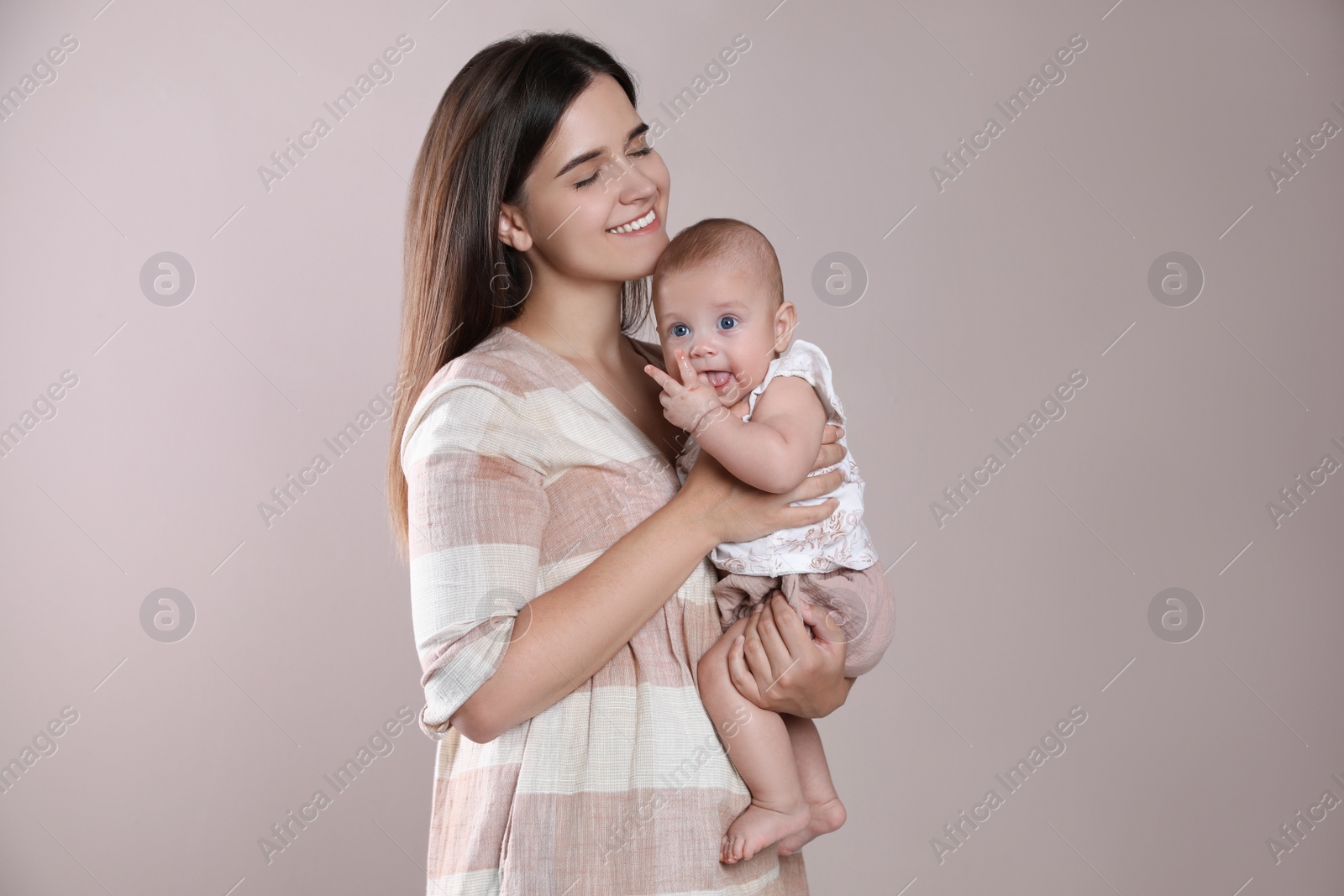 Photo of Beautiful mother with her cute baby on beige background